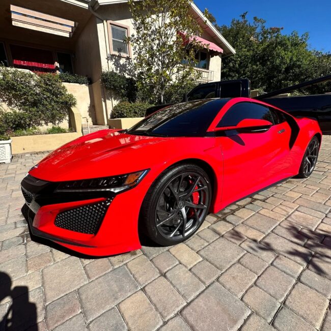 Red Acura parked in front of home.