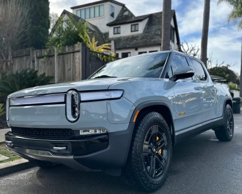 Grey Rivian freshly detailed and parked on the side of the street.