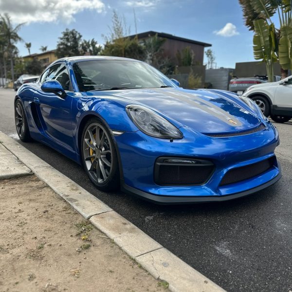 Blue Porsche parked on the side of the street and washed.